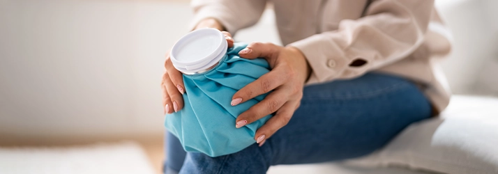 Woman With Ice Pack On Knee Sitting On Couch